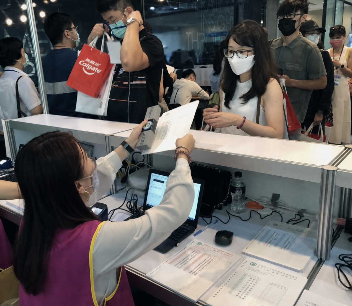 報到同仁使用筆電與現場文件，為與會者處理複雜資格核對與活動報到