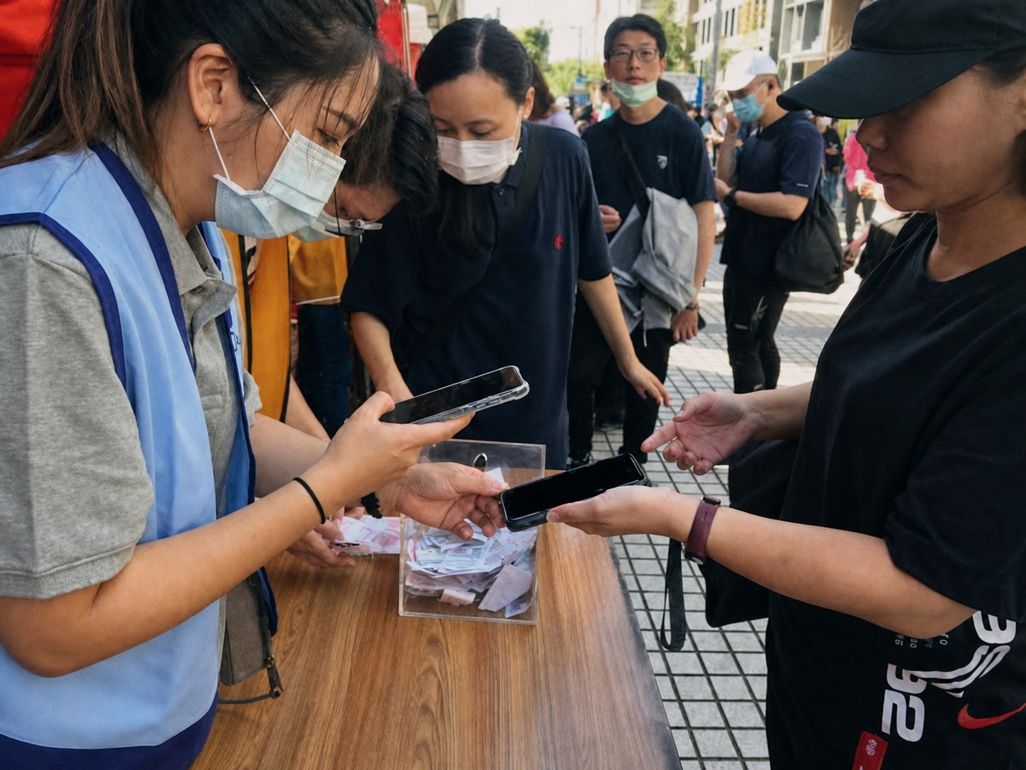 戶外活動報到同仁使用手機協助與會者查驗資料，後方有等待入場隊伍